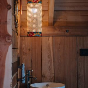 Hébergement insolite en bois avec un lavabo moderne et une lampe colorée.