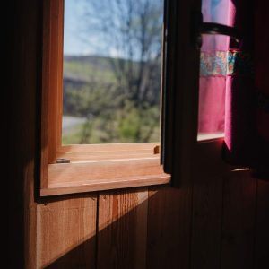 Cabane en bois avec vue sur la nature, lumière douce entrant par la fenêtre.