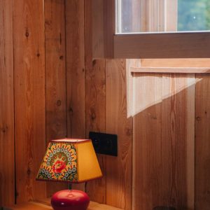 Hébergement insolite en bois avec une lampe colorée sur une table ensoleillée.