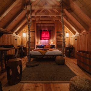 Chalet en bois chaleureux avec lit douillet et baignoire en bois. Ambiance cosy.