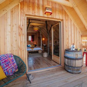 Cabane en bois avec terrasse, vue sur la nature, ambiance chaleureuse et cosy.