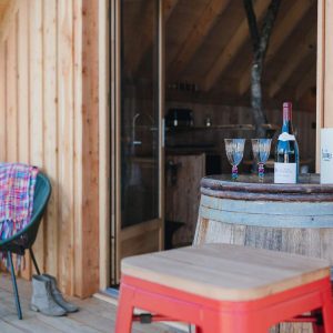 Cabane en bois en Provence-Alpes-Côte dAzur avec vue sur un verre de vin et des chaises colorées.