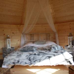 Hébergement insolite en Bretagne : cabane en bois avec lit douillet et lumière naturelle.