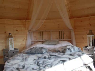Hébergement insolite en Bretagne : cabane en bois avec lit douillet et lumière naturelle.