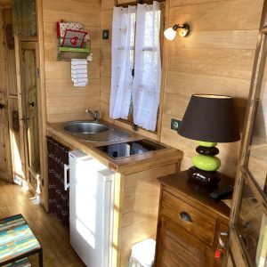 Charmante roulotte en bois avec kitchenette et lumière douce, idéale pour un séjour unique.