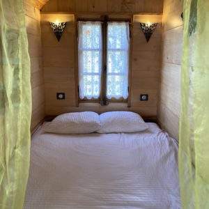 Chambre en bois douillette avec rideaux jaunes, idéale pour un séjour insolite.