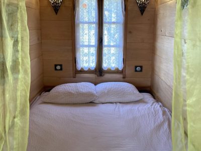 Chambre en bois douillette avec rideaux jaunes, idéale pour un séjour insolite.