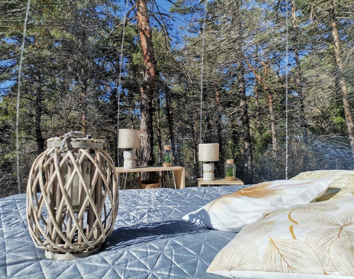 Cabane suspendue en pleine forêt, avec lit confortable et lanternes décoratives.