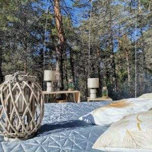 Cabane suspendue en pleine forêt, avec lit confortable et lanternes décoratives.