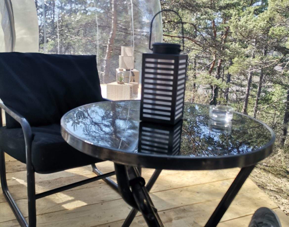 Hébergement insolite en bulle, table noire et lanterne dans un cadre naturel.