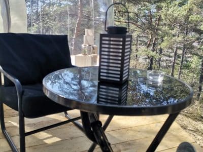 Hébergement insolite en bulle, table noire et lanterne dans un cadre naturel.