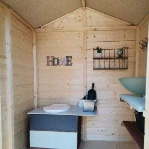 Cabane en bois cosy avec lavabo et décoration minimaliste, idéale pour un séjour unique.