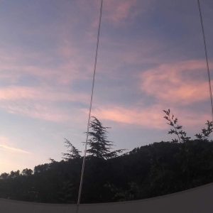 Hébergement insolite en bulle, vue sur un ciel coloré et des arbres verdoyants.