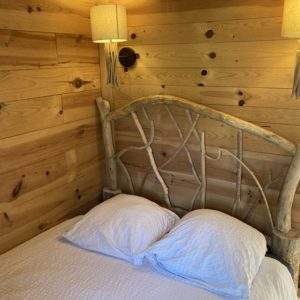 Chalet en bois avec lit en branches, ambiance chaleureuse et naturelle.