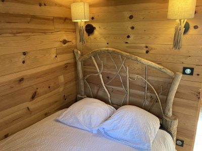 Chalet en bois avec lit en branches, ambiance chaleureuse et naturelle.