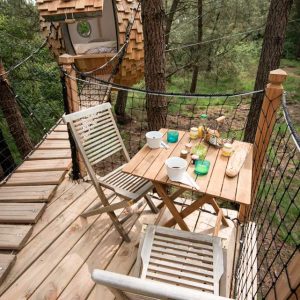 Cabane perchée en Bretagne, avec terrasse en bois et vue sur la forêt.