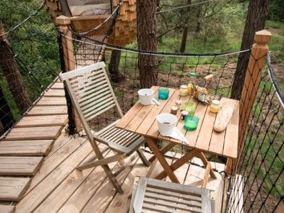 Cabane perchée en Bretagne, avec terrasse en bois et vue sur la forêt.