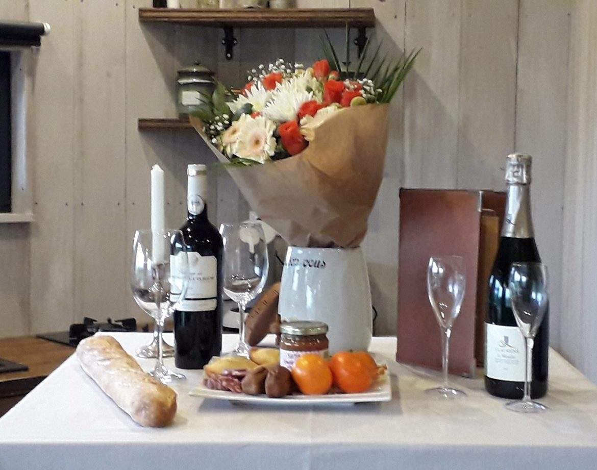 Hébergement insolite en Languedoc-Roussillon, table dressée avec fleurs et vins.