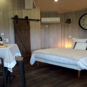 Chalet moderne en bois avec lit douillet et coin repas romantique.