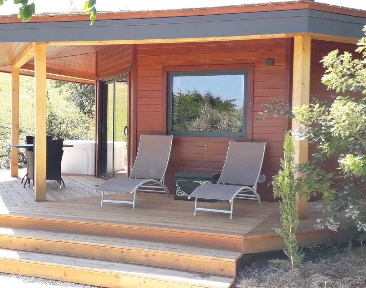 Cabane en bois avec terrasse ensoleillée et chaises longues à Languedoc-Roussillon.