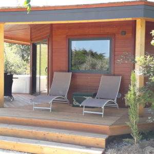 Cabane en bois avec terrasse ensoleillée et chaises longues à Languedoc-Roussillon.