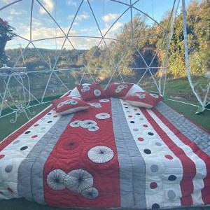 Dôme géodésique en Corse, lit douillet avec couette colorée et vue sur la nature.