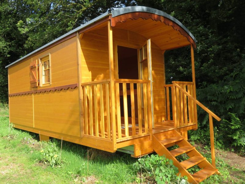 Charmante roulotte en bois avec balcon, entourée de verdure. Idéale pour un séjour nature.