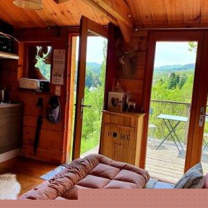 Cabane en bois avec vue panoramique sur la nature, ambiance chaleureuse et cosy.