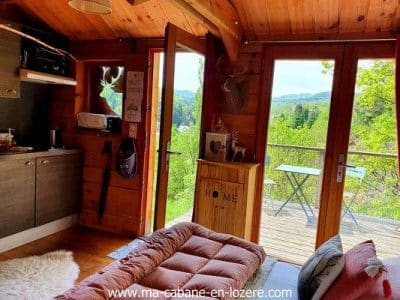 Cabane en bois avec vue panoramique sur la nature, ambiance chaleureuse et cosy.