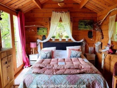 Cabane en bois cosy avec lit douillet et décoration chaleureuse. Parfaite pour un séjour nature.