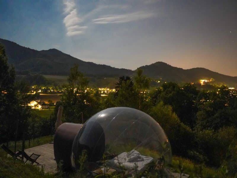 Hébergement en bulle transparente sous un ciel étoilé, avec vue sur les montagnes.
