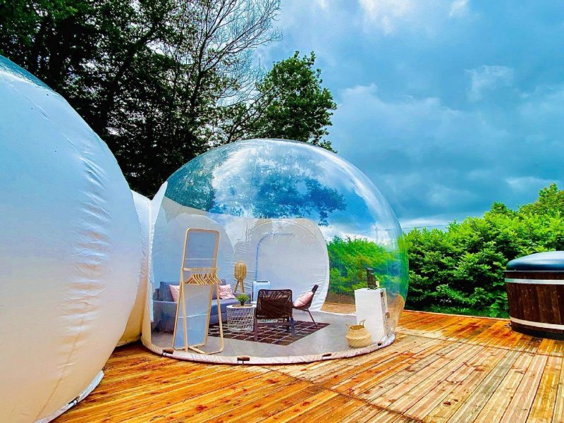 Hébergement insolite en bulle transparente, avec terrasse en bois et vue sur la nature.