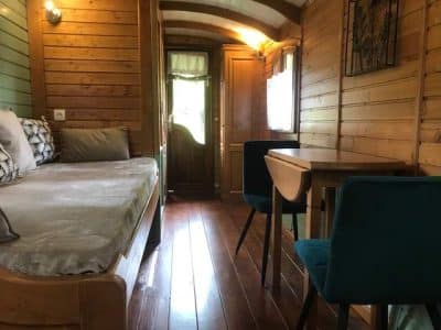 Hébergement insolite : roulotte en bois avec un intérieur chaleureux et lumineux.