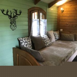 Hébergement insolite : cabane en bois avec un canapé confortable et des coussins décoratifs.