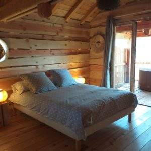 Chalet en bois avec lit douillet et accès à une terrasse privée.