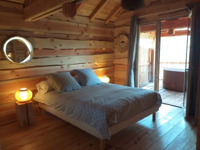 Chalet en bois avec lit douillet et accès à une terrasse privée.