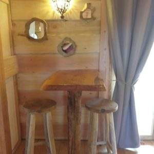 Hébergement insolite en bois en Auvergne-Rhône-Alpes avec table et tabourets rustiques.
