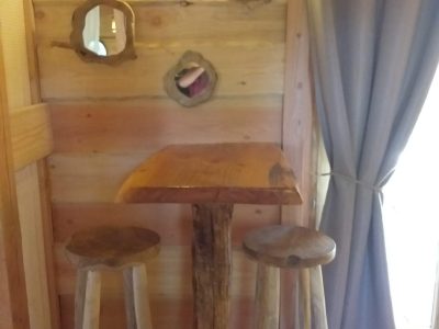 Hébergement insolite en bois en Auvergne-Rhône-Alpes avec table et tabourets rustiques.