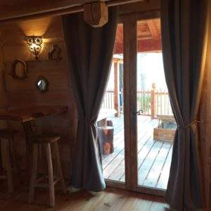 Cabane en bois avec une terrasse ensoleillée et des détails en bois chaleureux.
