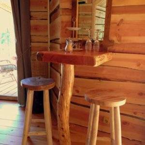 Hébergement insolite en Auvergne-Rhône-Alpes, intérieur en bois avec table et tabourets rustiques.