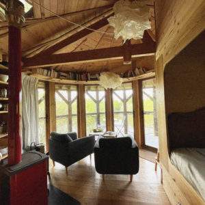 Cabane en bois avec vue panoramique, mobilier cosy et lumière naturelle.