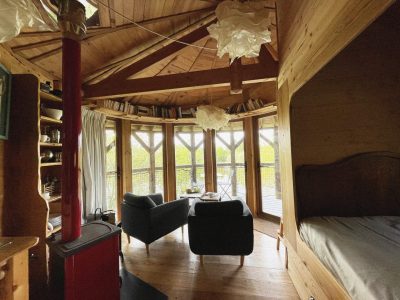 Cabane en bois avec vue panoramique, mobilier cosy et lumière naturelle.