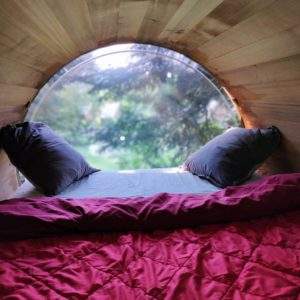 Cabane en bois avec vue panoramique, lit douillet et coussins confortables.