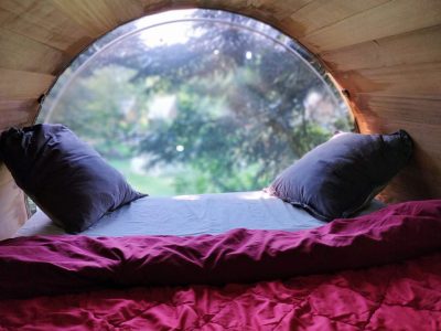 Cabane en bois avec vue panoramique, lit douillet et coussins confortables.