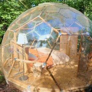 Dôme transparent en bois, offrant une vue imprenable sur la nature environnante.