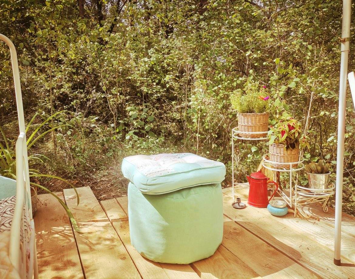 Hébergement insolite en pleine nature, avec un pouf coloré et des plantes décoratives.