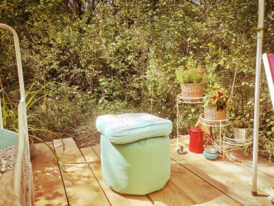 Hébergement insolite en pleine nature, avec un pouf coloré et des plantes décoratives.