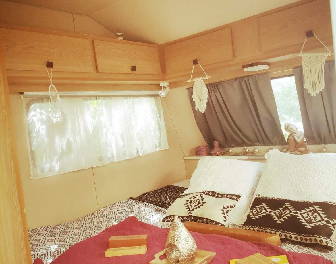 Hébergement insolite en caravane, intérieur cosy avec lits douillets et décor boho.