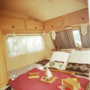 Hébergement insolite en caravane, intérieur cosy avec lits douillets et décor boho.