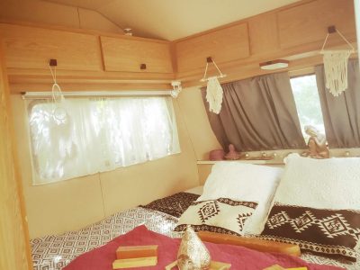 Hébergement insolite en caravane, intérieur cosy avec lits douillets et décor boho.